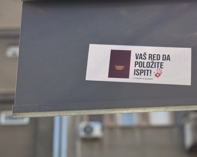 A sign with a sticker on it in front of a building