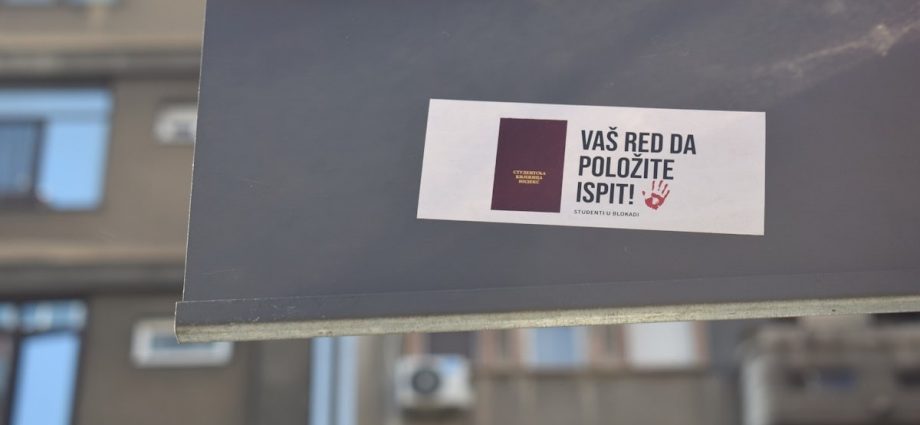 A sign with a sticker on it in front of a building